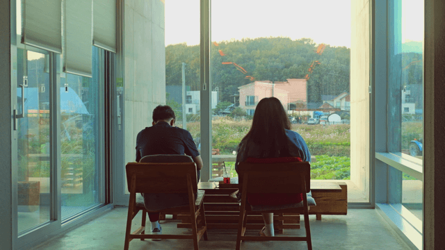Two people sitting indoors with a cafe view