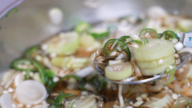 Spoon lifting scallion and chili soy seasoning sauce