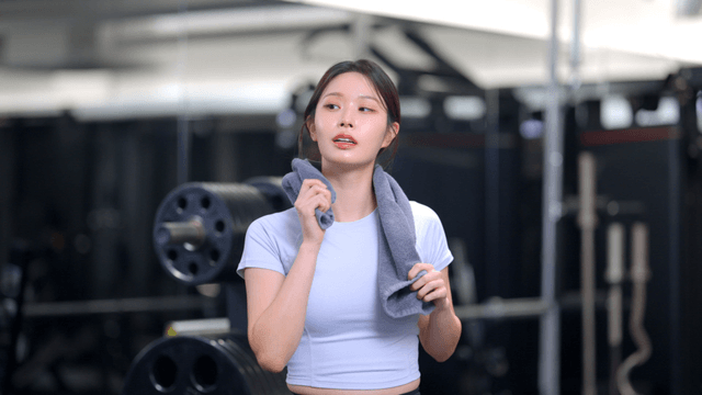 Young woman resting after workout wiping sweat with towel