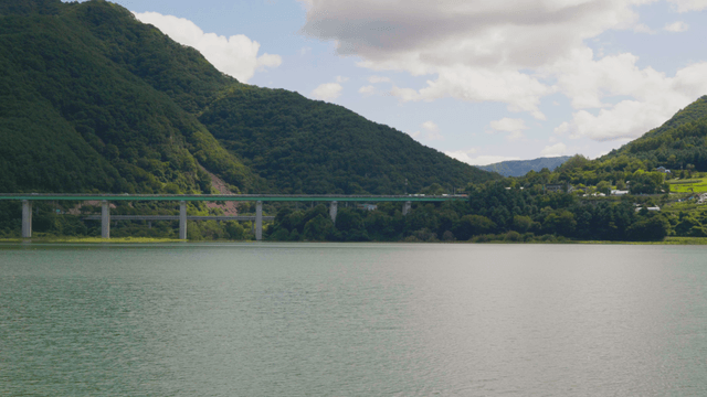 Bridge stretching across calm lakeside mountains