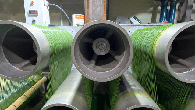 Green threads winding onto industrial spool