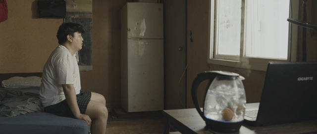 Man sitting on a bed in a dim room
