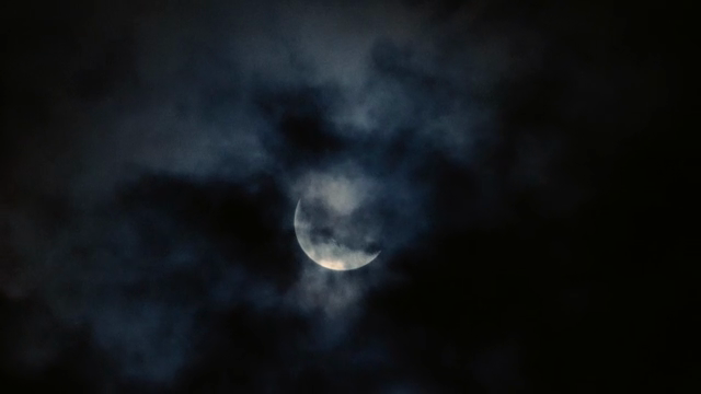 A crescent moon surrounded by clouds