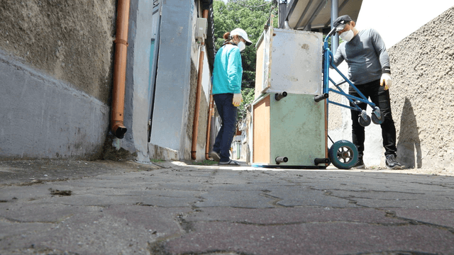 Workers moving a shelf in a narrow alley
