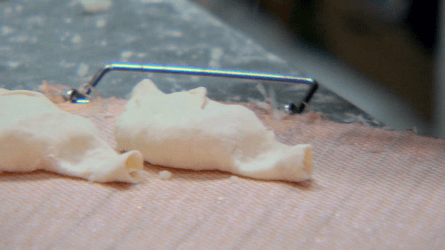 쟁반 위에서 만두 반죽을 모양내는 손