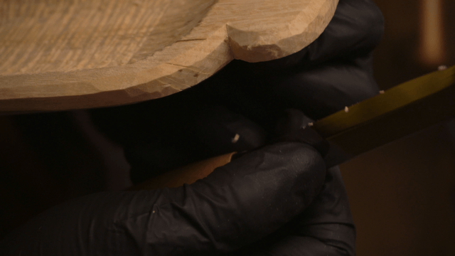 Woodcraft artisan carving wooden piece with precision knife