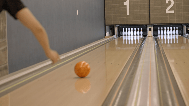 Bowling ball rolling towards pins