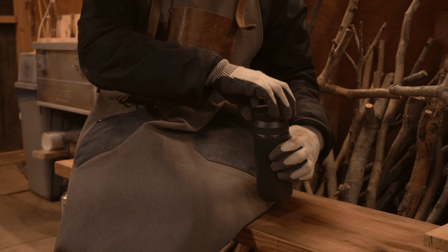 Craftsman opening a tumbler lid in woodworking studio