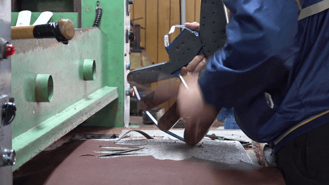 Worker cutting leather to fit glove mold
