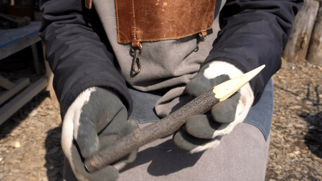 Woodcraft artisan inspecting sharp wooden sticks outdoors