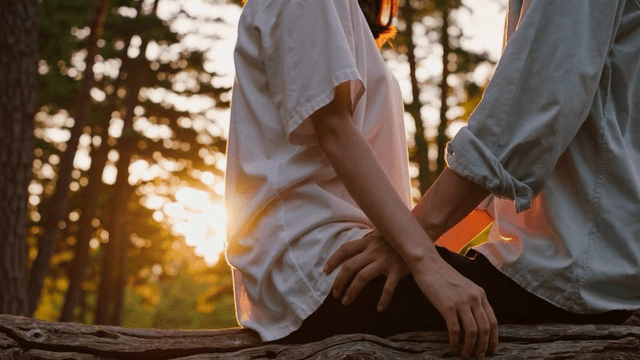 A couple sitting on a log in the forest