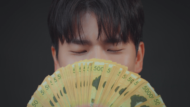 A person holding a fan of currency notes