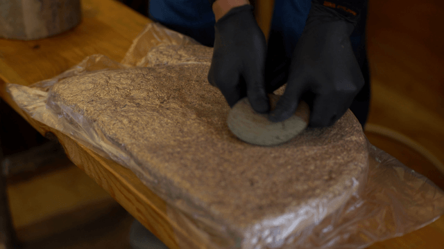 Woodcraft artisan pressing wood and sawdust with a stone