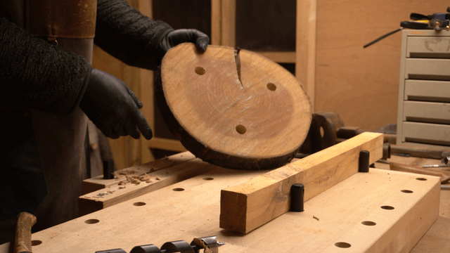 Craftsman inspecting a wooden board with holes in workshop