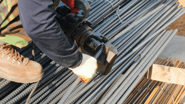 Worker cutting steel bars at a construction site
