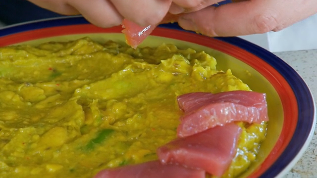 Tuna slices being placed on guacamole