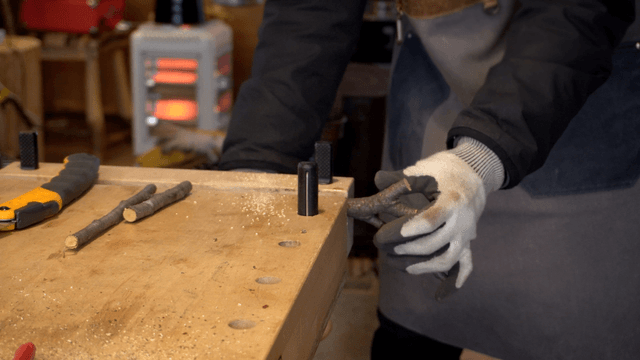 Craftsman sawing a branch on a wooden stand