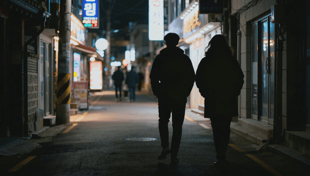 People walking at a bright night crossroads