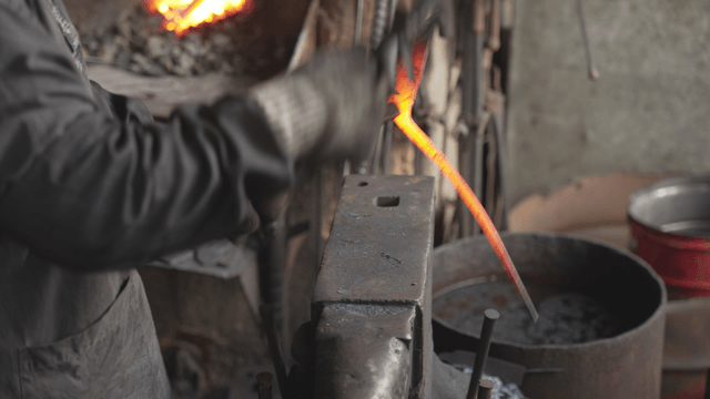 Blacksmith shaping hot metal with hammer