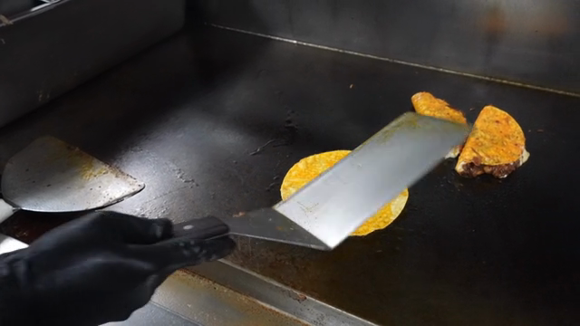 A taco being cooked on a hot griddle