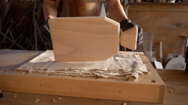 Woodcraft artisan examining handmade wooden cutting board in workshop