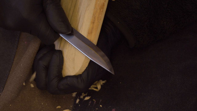 Hands carving wood with a sharp knife
