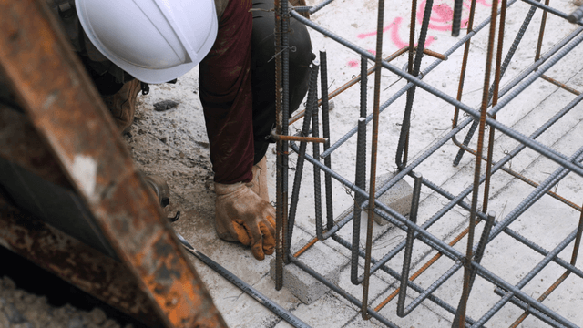 Worker assembling steel rebar at a construction site