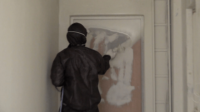 Worker painting a door with a spray gun