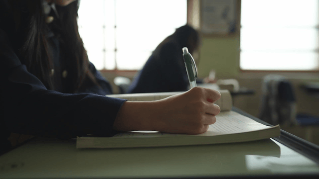 Student writing notes in a classroom