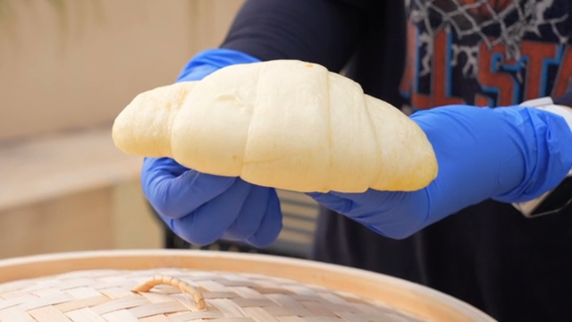 Freshly steamed bread held by gloved hands