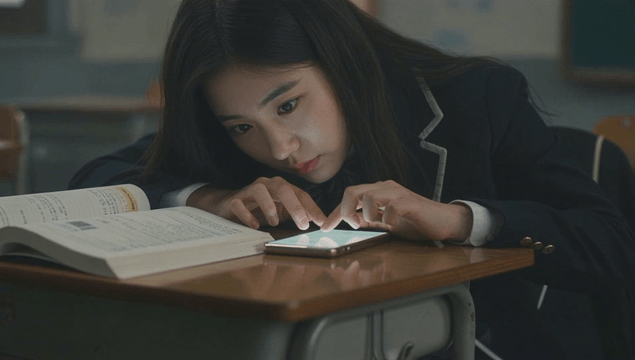 Schoolgirl using smartphone alone in dark classroom