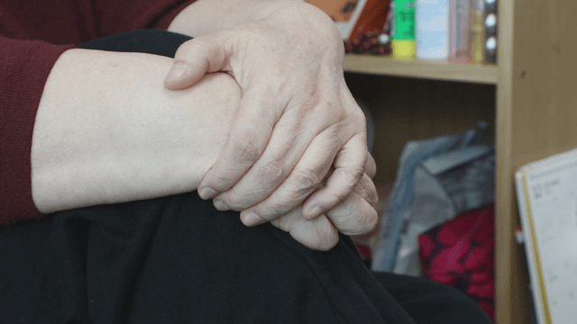 Elderly hands resting on a knee indoors