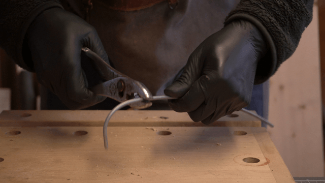 Artisan bending metal wire with pliers