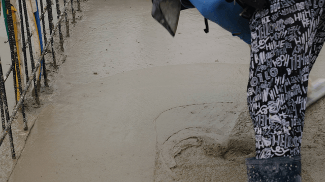 Worker smoothing wet concrete surface