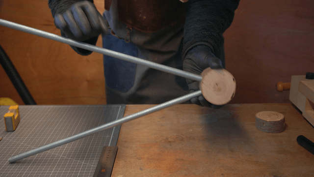 Woodcraft artisan assembling a metal rod onto a wooden piece