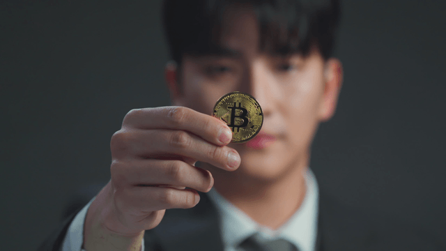 A man holding a Bitcoin coin
