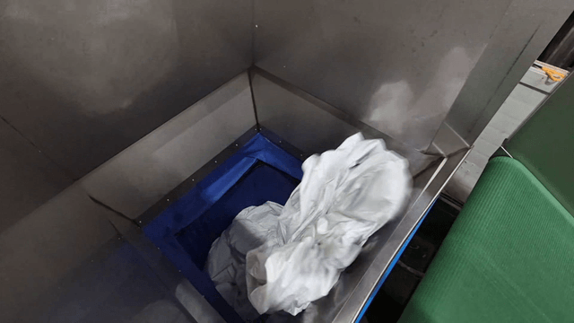 White fabrics gathered on conveyor belt in factory machine