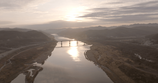 A serene river with a bridge at sunset