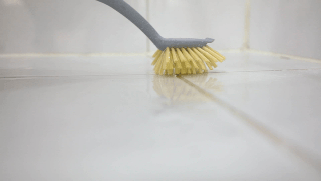 Cleaning a tiled floor with a brush