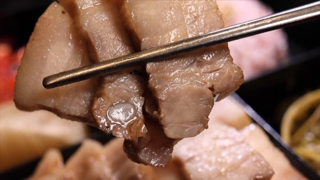 Chopsticks holding slices of bossam