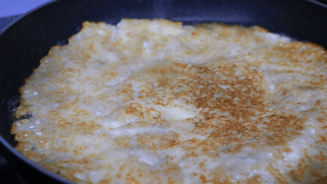 Potato pancake cooking in a frying pan