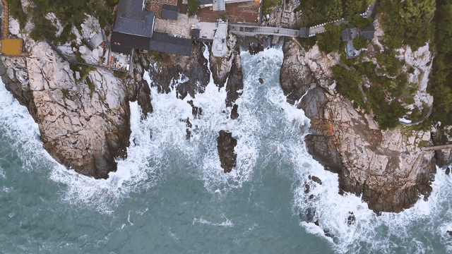 Waves striking the coastal cliff with a seaside temple