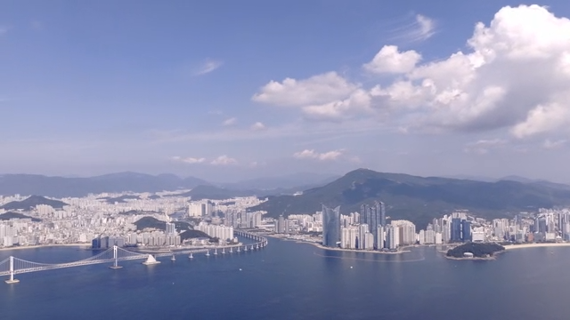 Coastal city with high-rise buildings and a sea bridge under clear sky