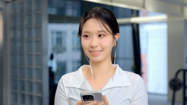 Young woman using smartphone with earphones at gym