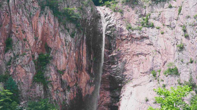 Thin waterfall flowing along rocky cliff