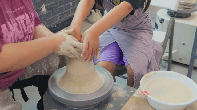 도자기 물레에서 점토를 빚는 두 사람