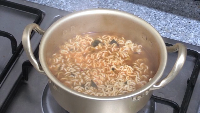 라면이 들어있는 냄비 뚜껑을 여는 사람