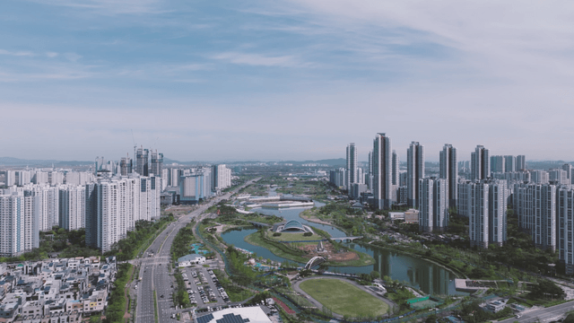 Lake park beside boulevard with high-rise buildings