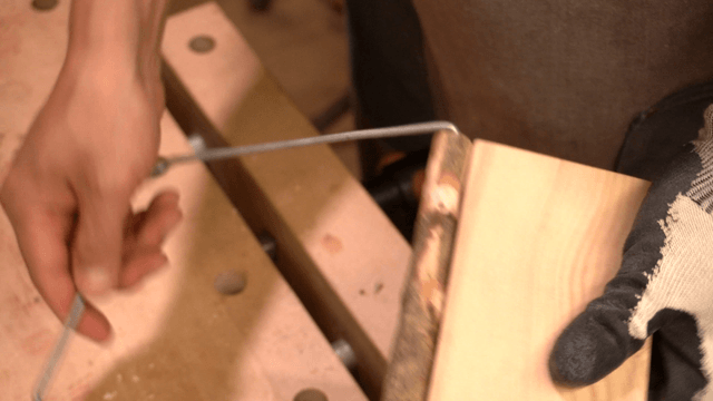 Hands connecting metal wires through holes in wooden pieces