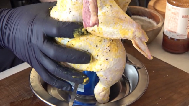 Seasoned raw chicken on top of a beer can